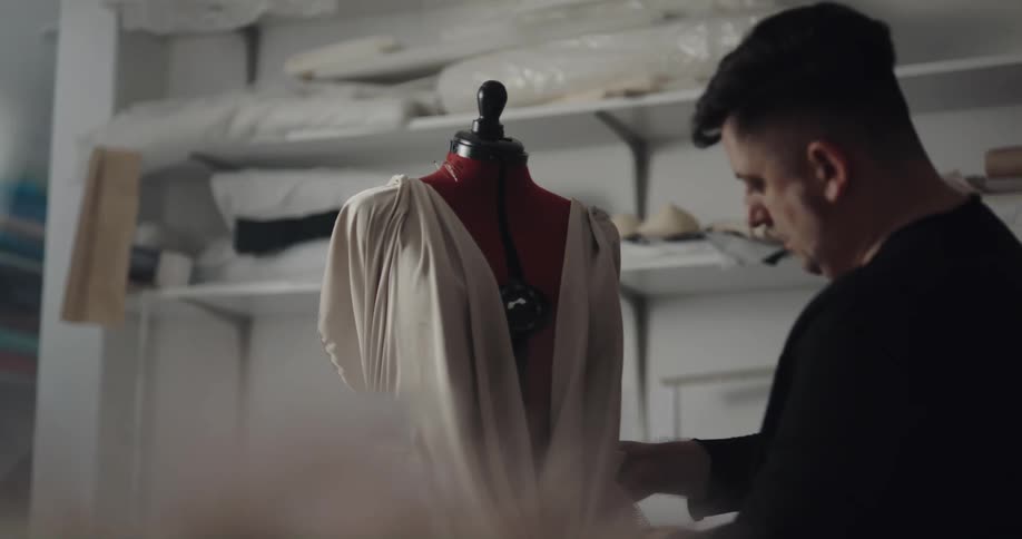 A seamstress pins clothing on a mannequin