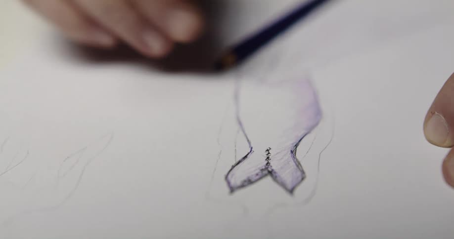 Designer drawing a dress on a piece of paper with a pencil