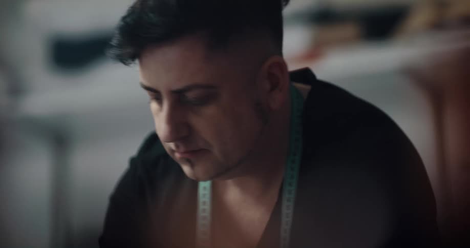 Fashion designer wearing a measuring tape over his neck working inside a dimly lit room