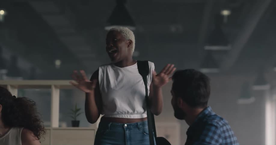 Man hugs woman and then he and other friends sit while she stands and talks