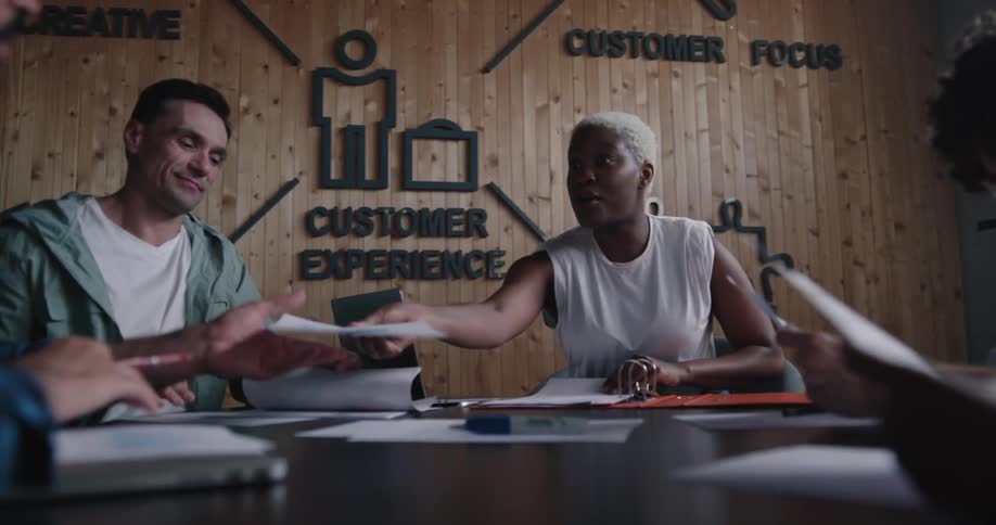 A woman leads a business meeting handing out reports and talking