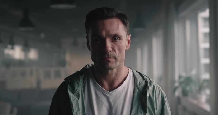 A man is standing by a window indoors