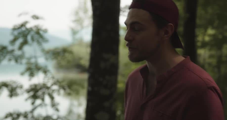 Angry man shouting at someone in the middle of a grove next to a big lake