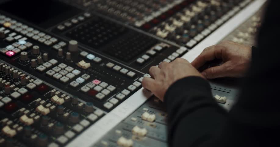 Person sits at large control panel with their hands on sliders