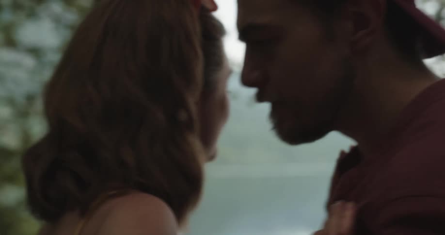 Man and woman standing near a lake while hes trying to hug her and she keeps angrily pushing him away