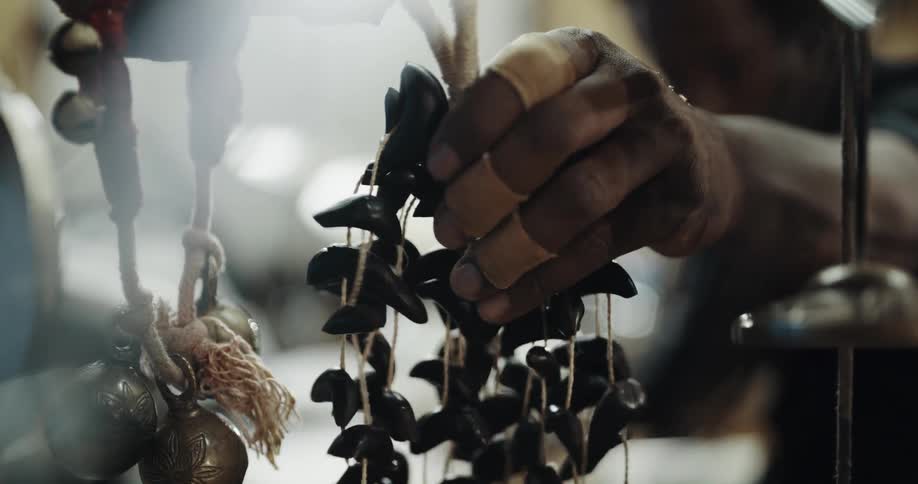 Man reaches with his hand and shakes a bunch of beans that are strung together with string