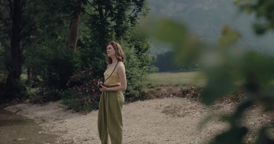 White woman standing outdoors taking pictures of the surroundings using a digital camera