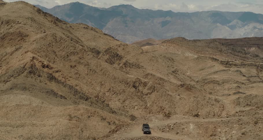A truck parked on a dirt road high up in mountains