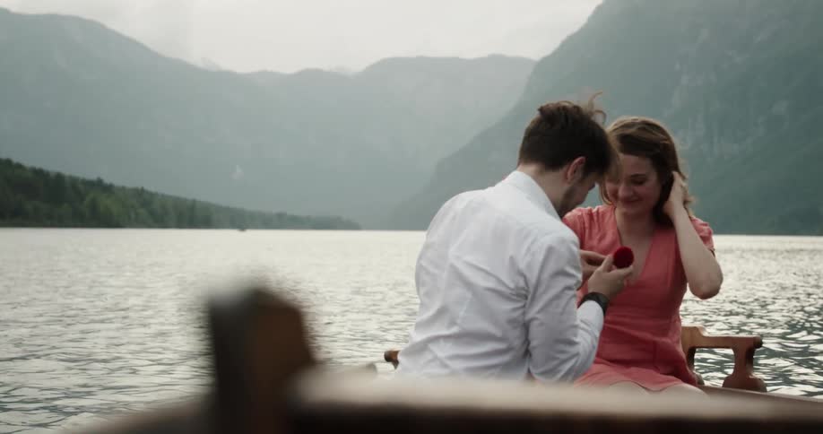 Man proposing to his girlfriend in a wooden canoe in the middle of the lake