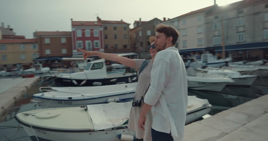 A couple hold hands while sightseeing along a river and pier