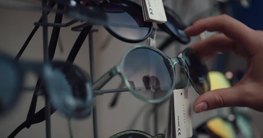 Woman picks up a pair of sunglasses from a rack on a street shop