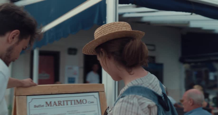 Man and woman read the menu on an outdoor easel at a restaurant