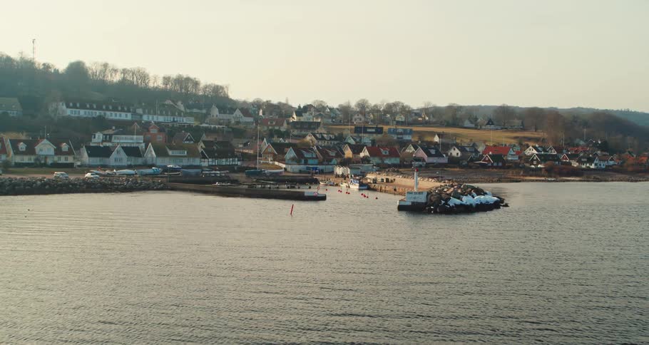 Aerial view of the bay in front of a a calm small coastal town close to the ocean at morning