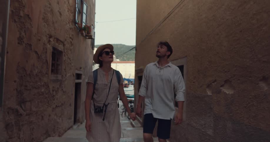 Young happy couple on vacation kiss while walking through an alley in a small town