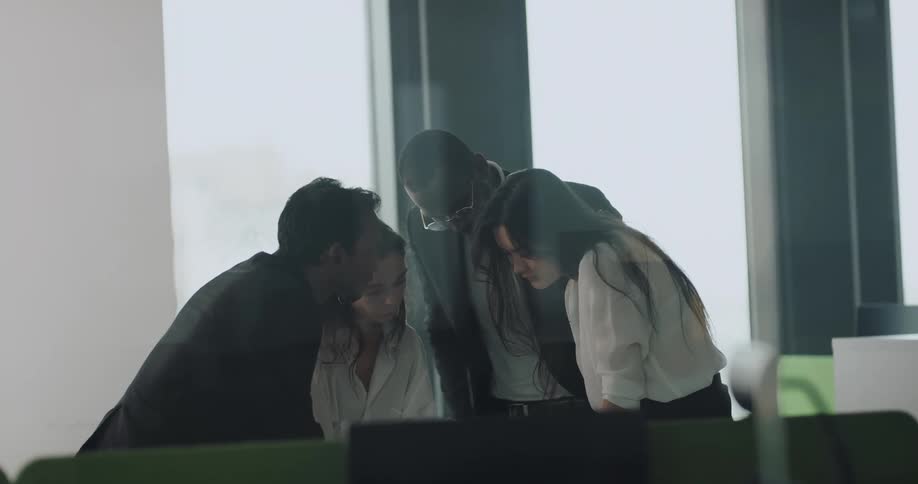 A group of coworkers huddled together talking and trying to solve a problem