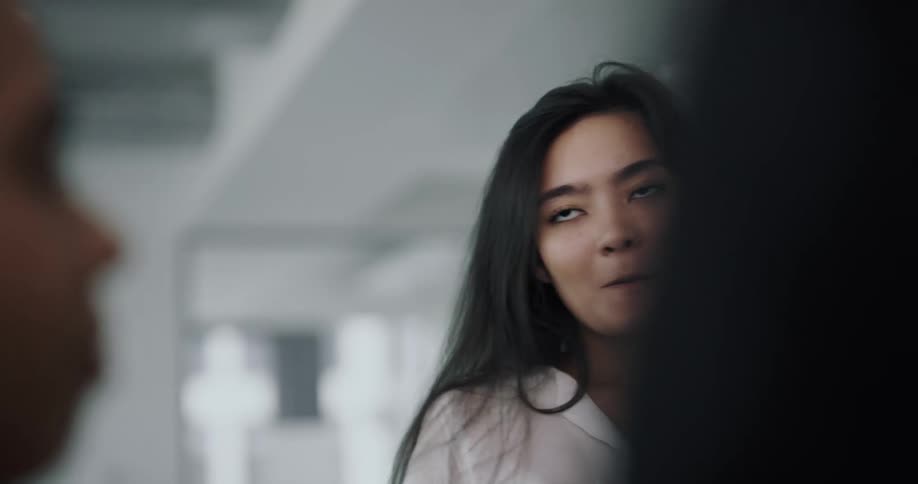 A young woman talks with a group of people while standing in an office during the day