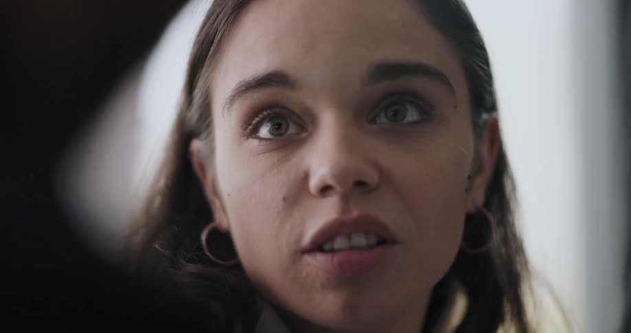 Close up of the face of a woman talking to another person inside a room