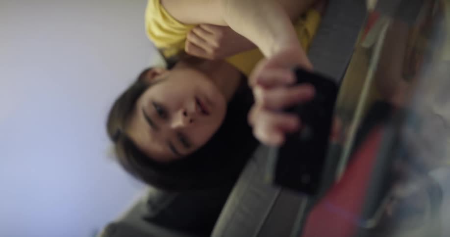 Young woman taking a nap on a couch at home wakes up to a call on her phone