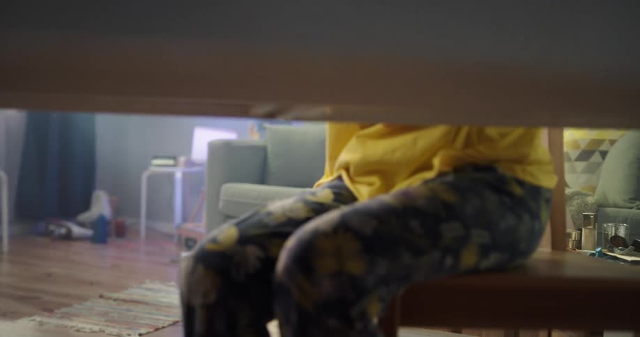 Young asian woman getting up from the couch and sitting down at the desk to study on her laptop and notebook