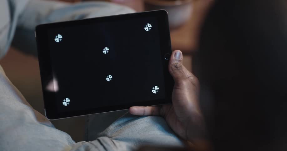 Black man sitting on the couch with his legs up holding a tablet