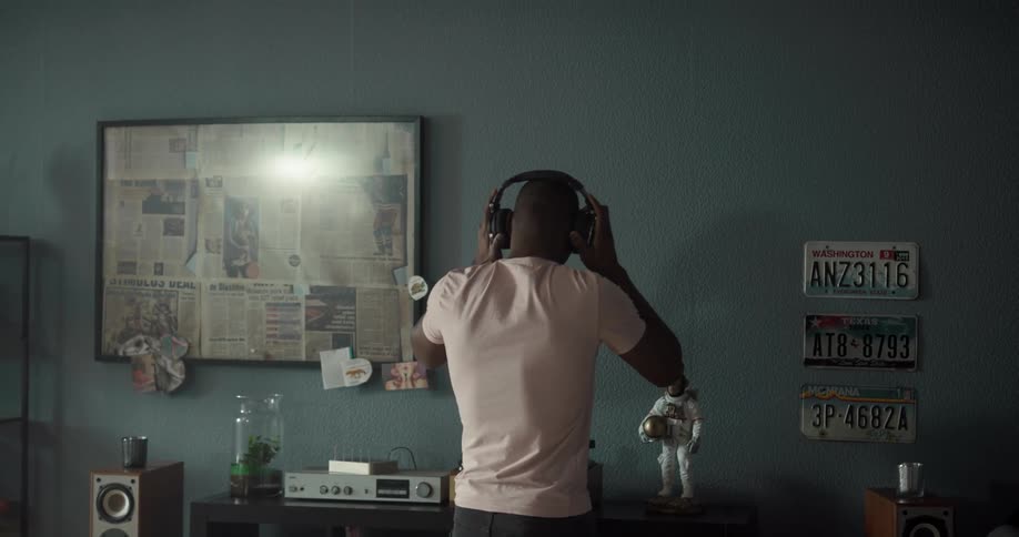 A man puts on a vinyl and headphones and dances in his apartment