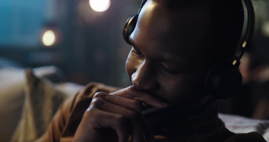 A man talks into a headset while sitting on a sofa indoors