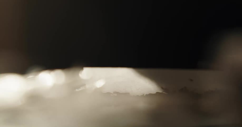Close up of a man sprinkling chopped tobacco over rolling paper