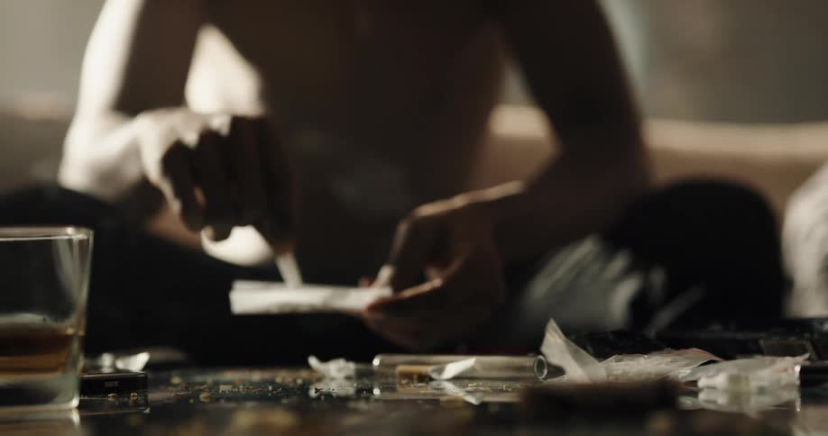 Man squeezes tobacco into a piece of cigarette paper