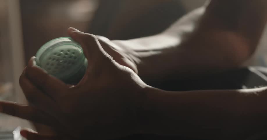 Substance is placed inside a round plastic green container then the container is twisted to grind up the contents