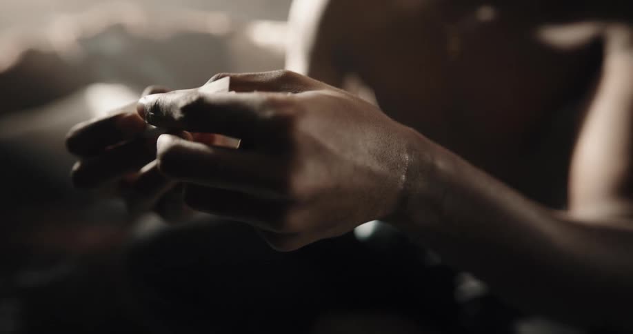 Black man sitting on the couch rolling a joint