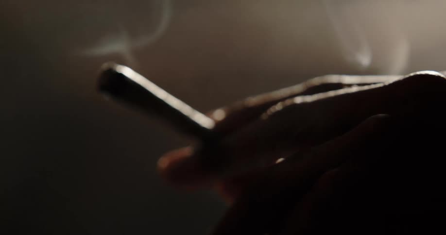 Hand of a man holding a cigarette a man is smoking