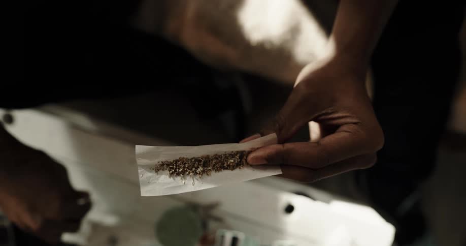 Hands of a man rolling a marijuana joint