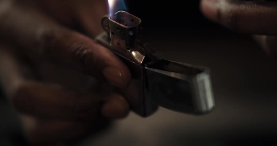Flame from a lighter is being held under a spoon that has a bent handle