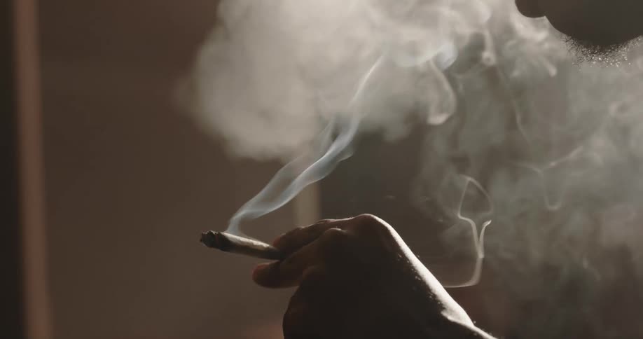 Man sitting on the couch holding a cigarette and smoking