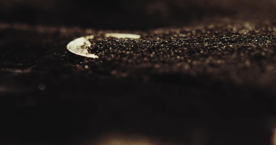 Particles are blown away revealing a gold plated bitcoin