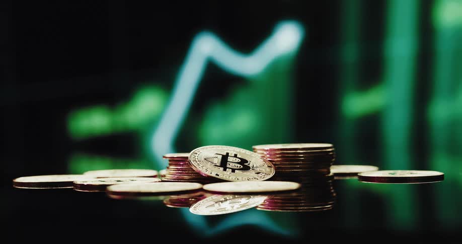 Small stack of gold bitcoins on a counter against green lights background