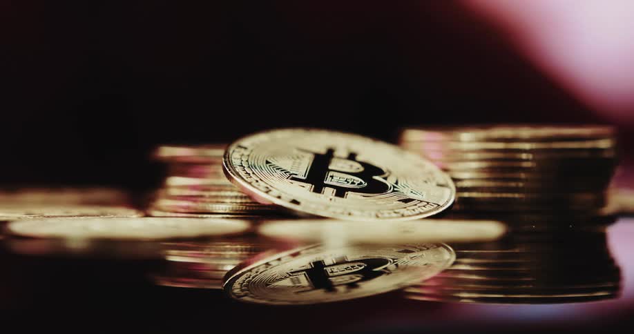 A stack of golden colored coins have the bitcoin cryptocurrency logo on them