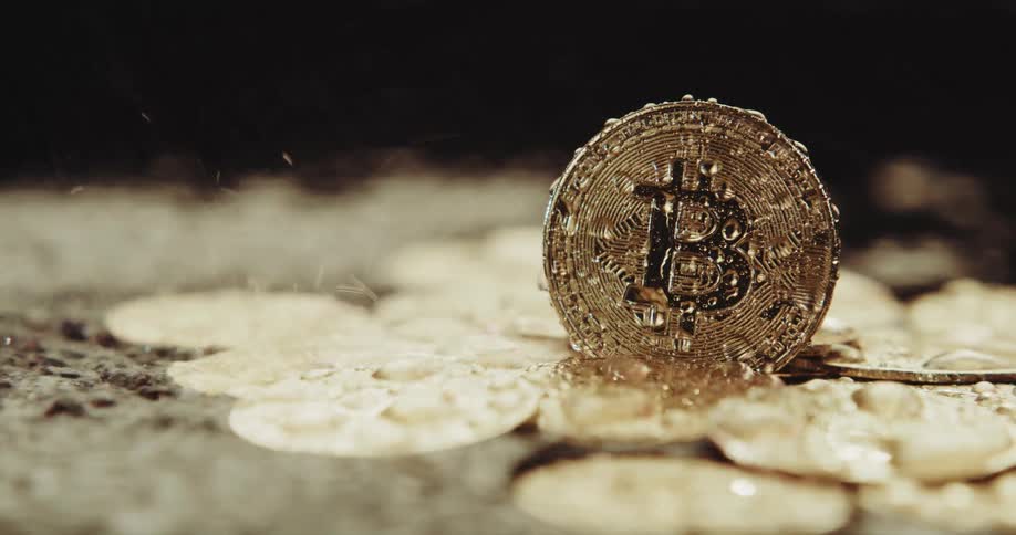 Water rains down and splashes on gold bitcoins