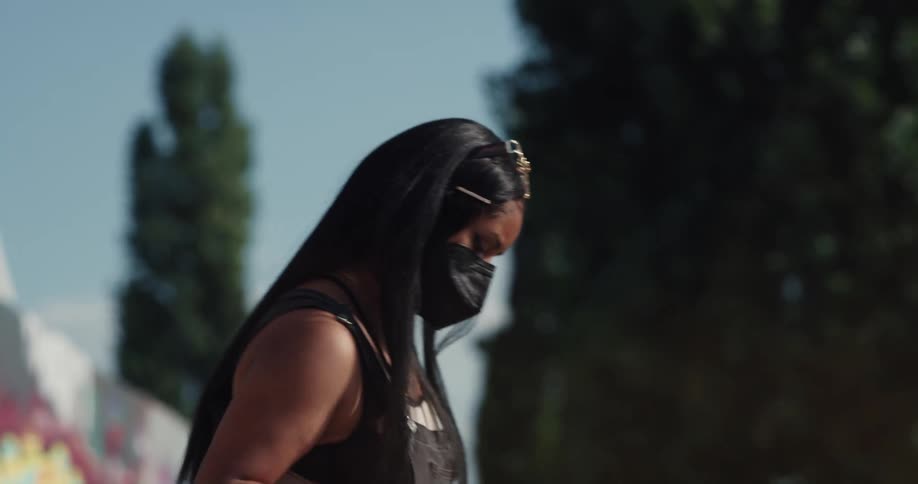 Woman wearing a face mask choosing which spray paint can she is going to use to do graffiti in a public space outdoors