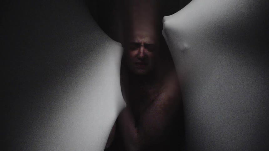 A woman is surrounded by ghost like hands pushing towards her through sheer fabric