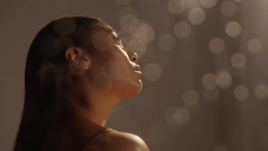 Model looking up behind a wet window with water drops running down