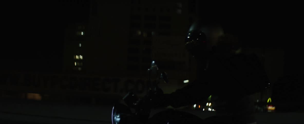Person riding a motorcycle on a road in the city street at night