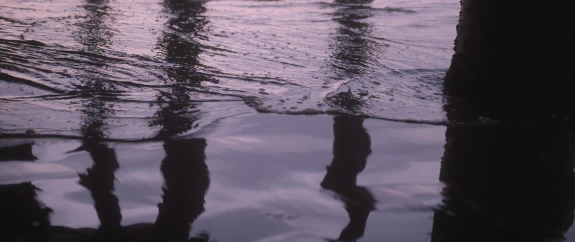 The tide washes into the shore beneath a boardwalk during the day