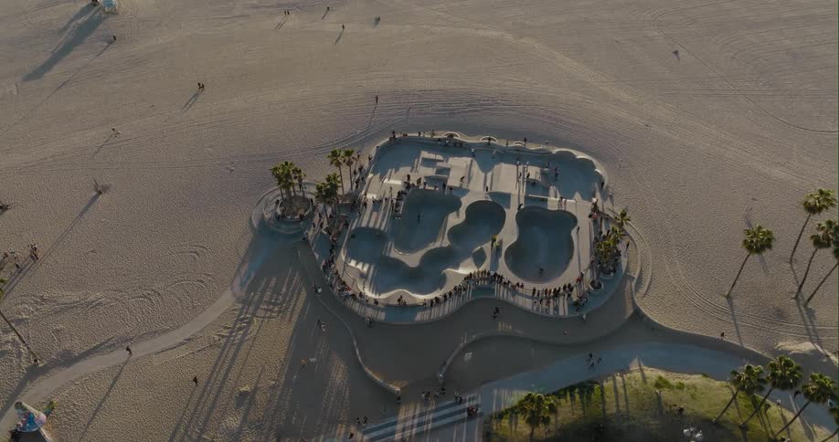 An elaborate skate park next to the beach has many people skating around