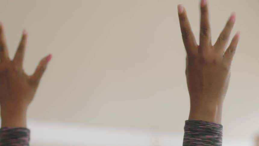 Female exercise instructor guides others while sitting in room