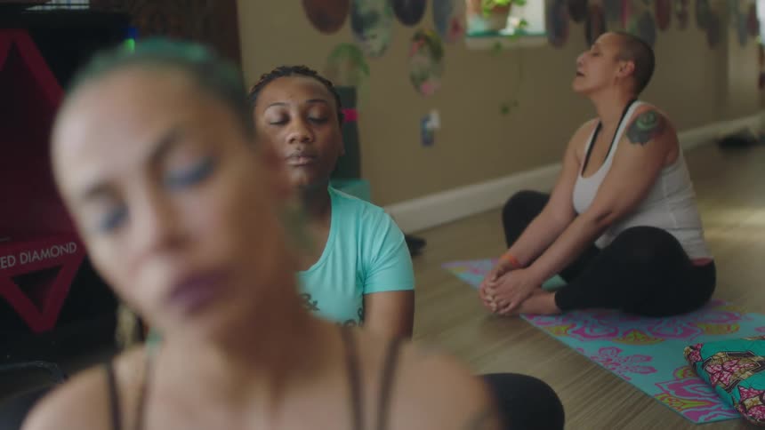 Women do yoga while sitting on yoga mats on the floor