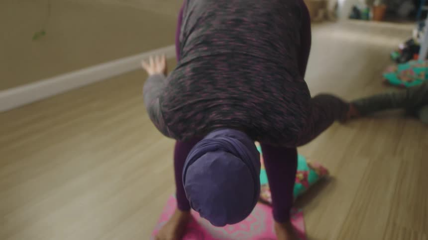 A woman raises her arms while stretching during a yoga class