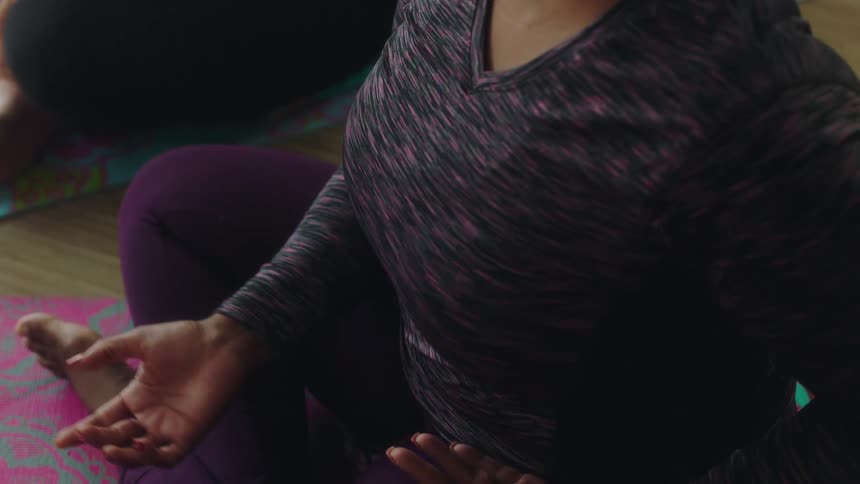 Women in a yoga class sit and chat