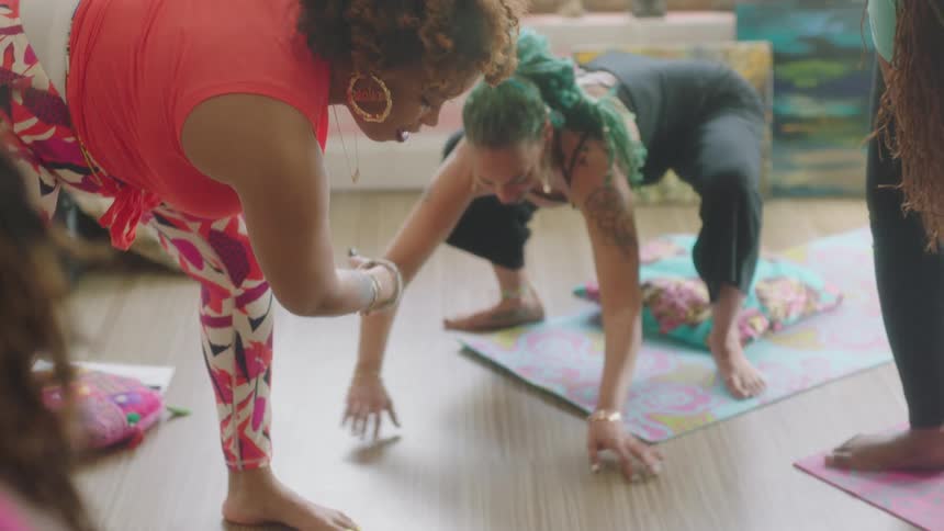 Group of barefoot women wearing sports clothes stretching over yoga mats