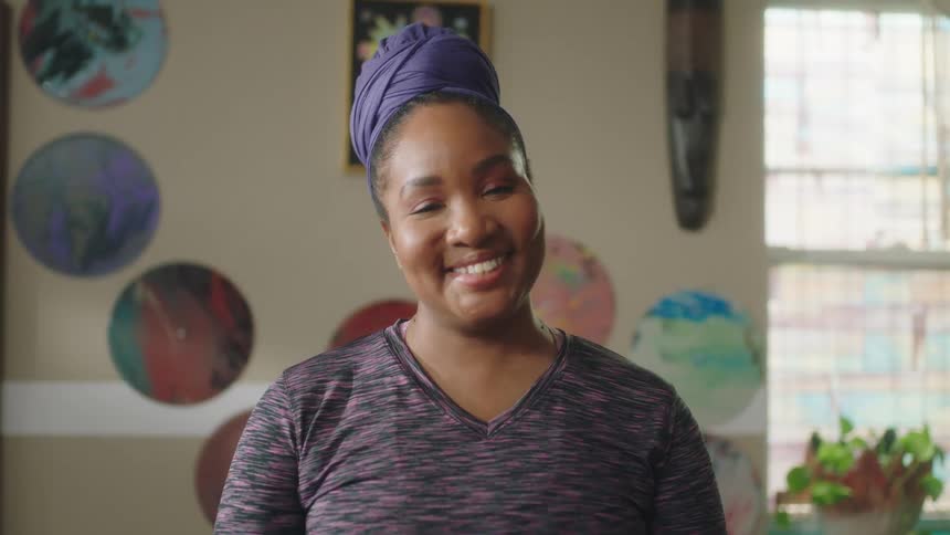 Young woman standing in a room at home looks at the camera smiling